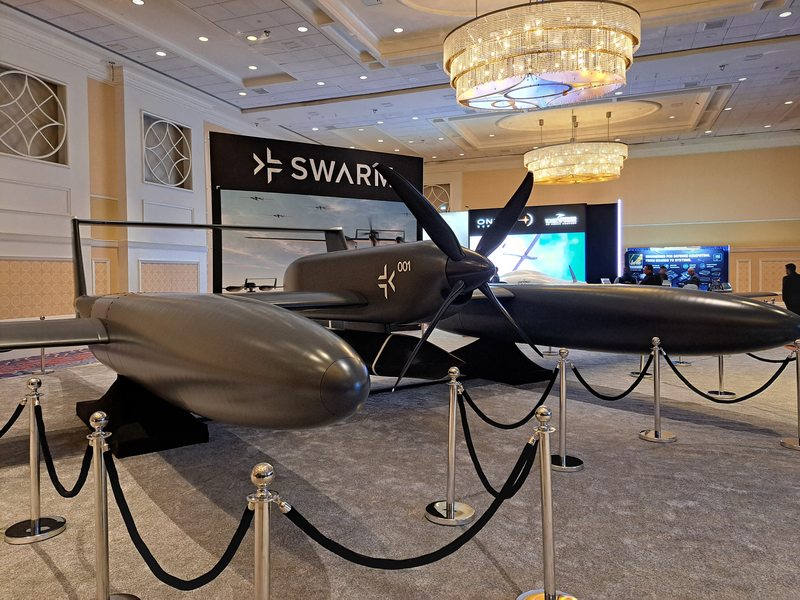Swarm Aero's Gamera mockup displayed behind ropes inside a conference hall.