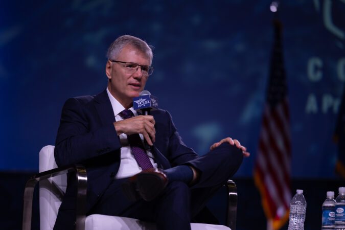 Secretary of the Air Force Troy Meink speaking into a microphone while seated at the conference.