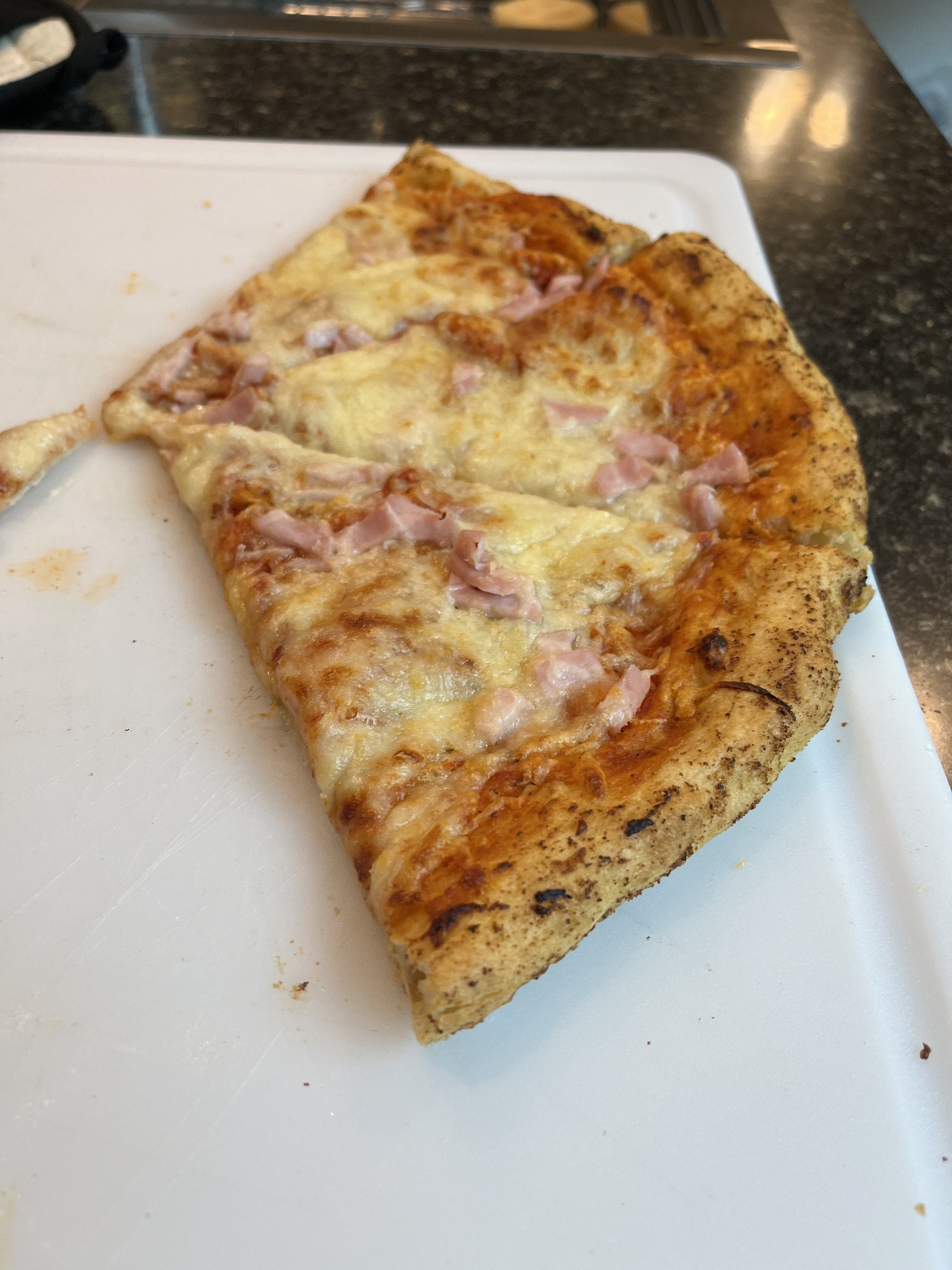 Three slices of pizza with cheese and a pink diced topping on a white cutting board.