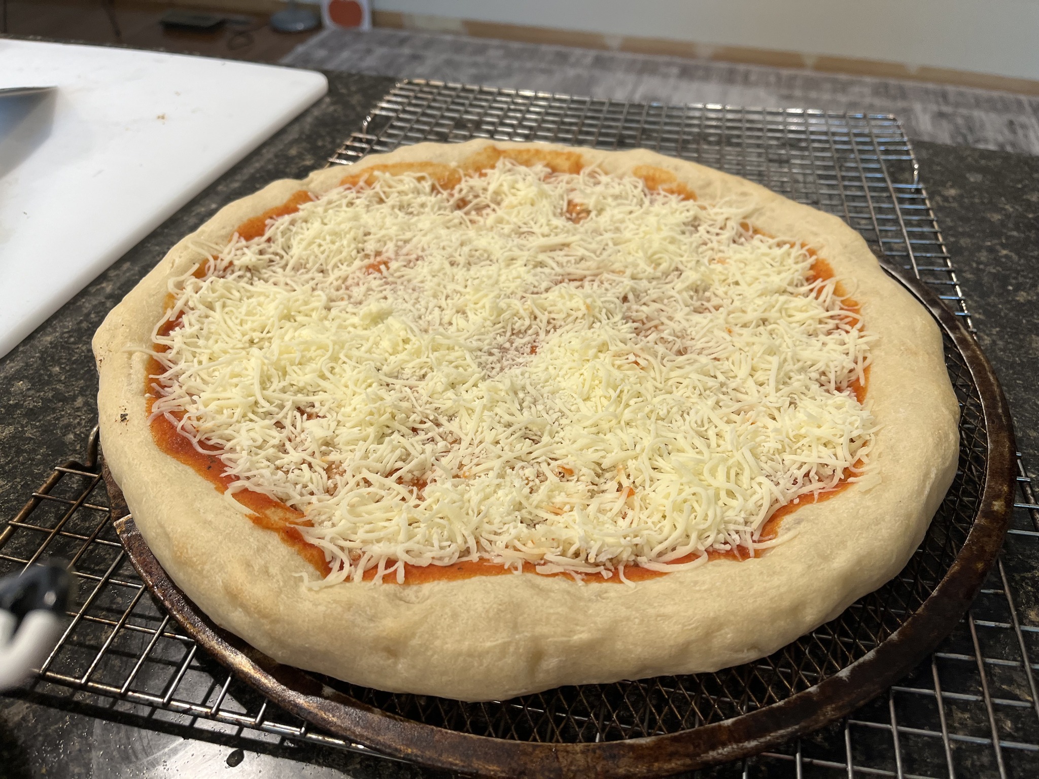 The same pizza base after grated cheese has been added over the sauce.