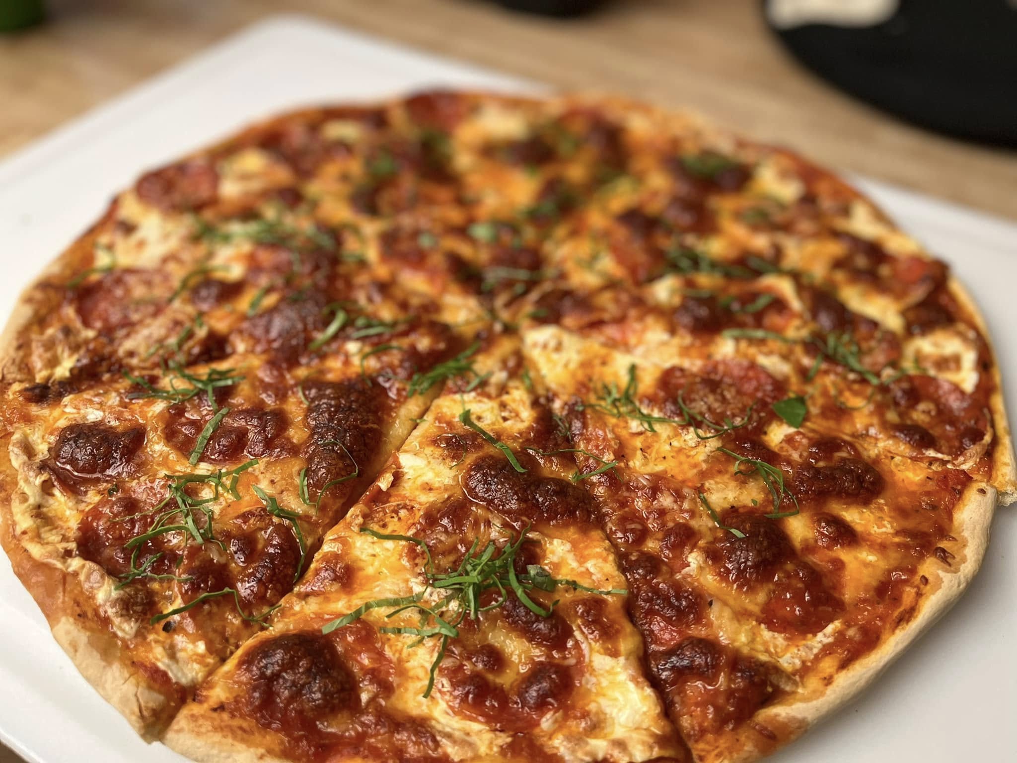 A whole sliced pepperoni pizza on a white plate.