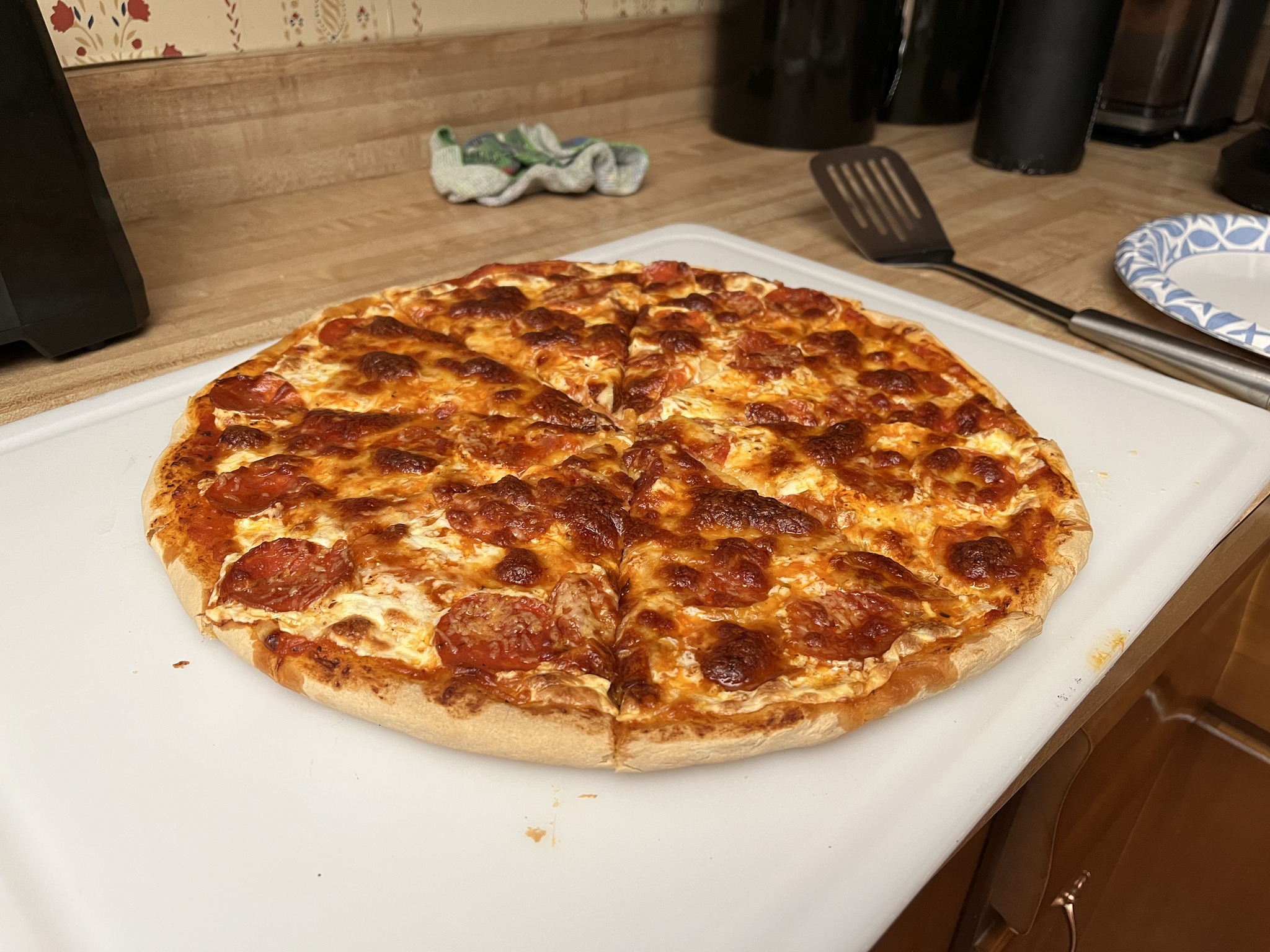 The first-day-of-school pepperoni pizza on its cutting board before the green garnish was added.