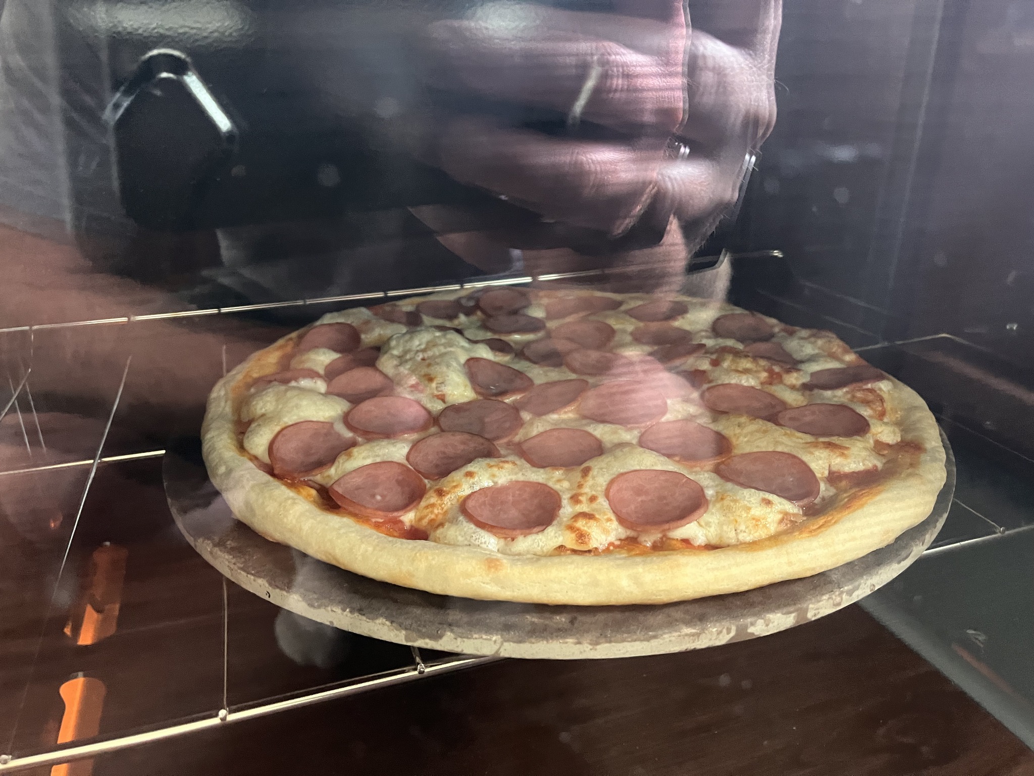 The same pizza baking directly on a round stone inside a kitchen oven.