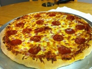 A homemade pizza topped with pepperoni and cheese on a round metal pan.