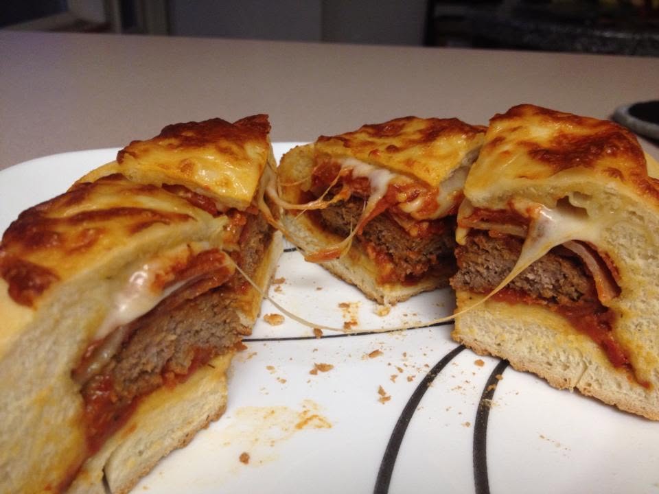 A pizza-dough-wrapped burger cut into wedges, with melted cheese and red sauce visible inside.
