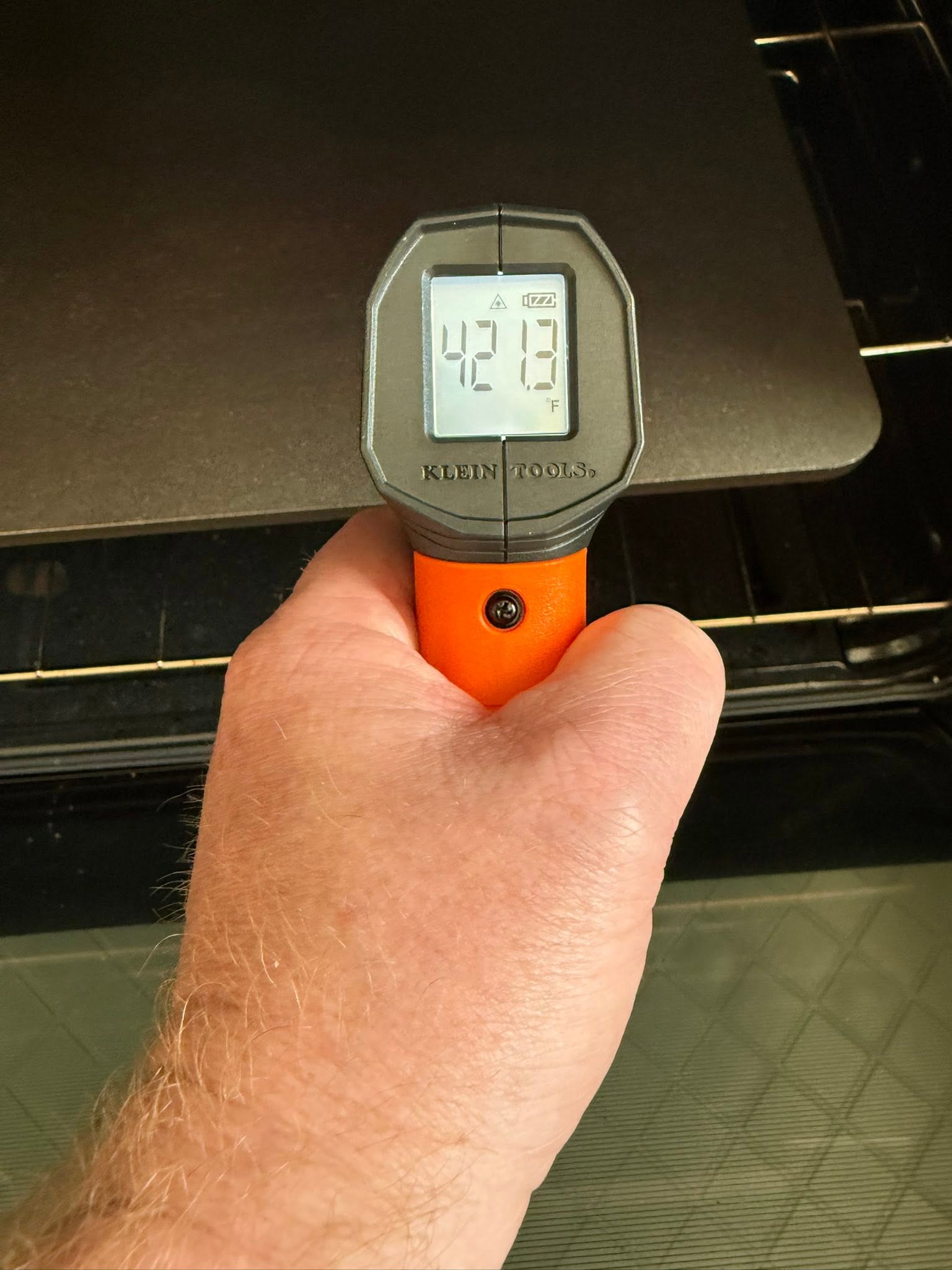 Infrared thermometer showing 421.3 degrees Fahrenheit while pointed at the baking surface inside the oven.