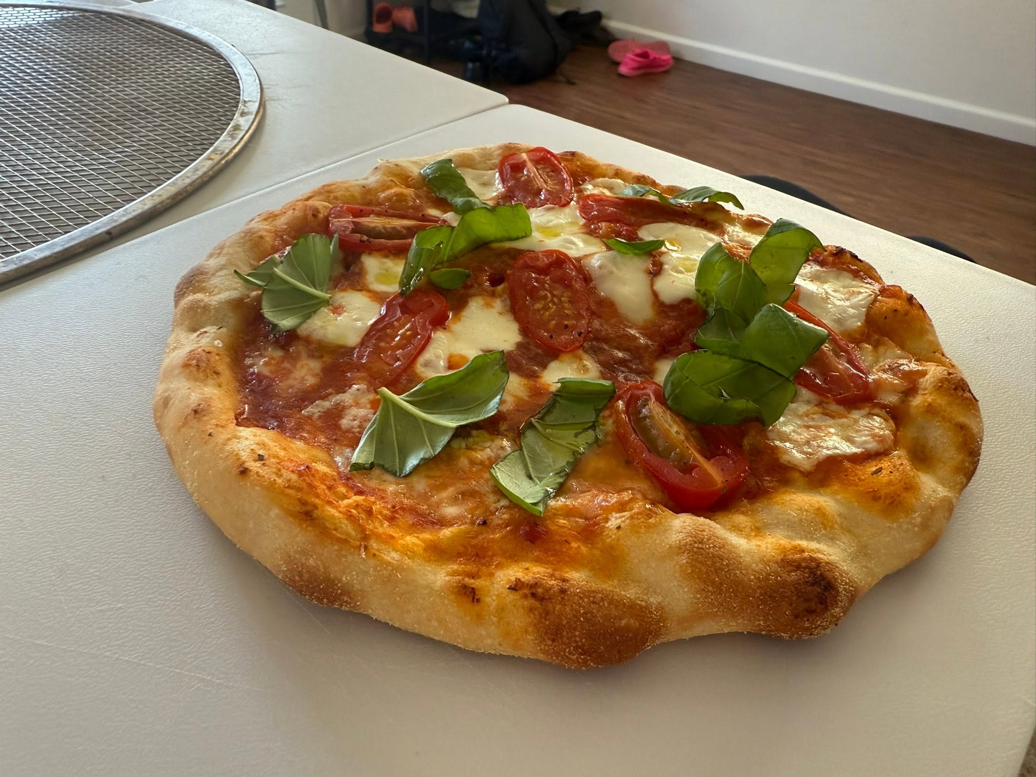 A second close view of the finished pizza topped with cheese, tomatoes and green leaves.