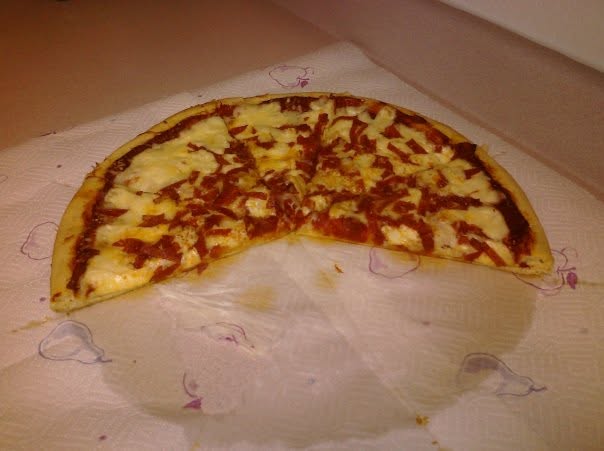 A homemade pepperoni pizza with several slices removed, resting on paper towels.